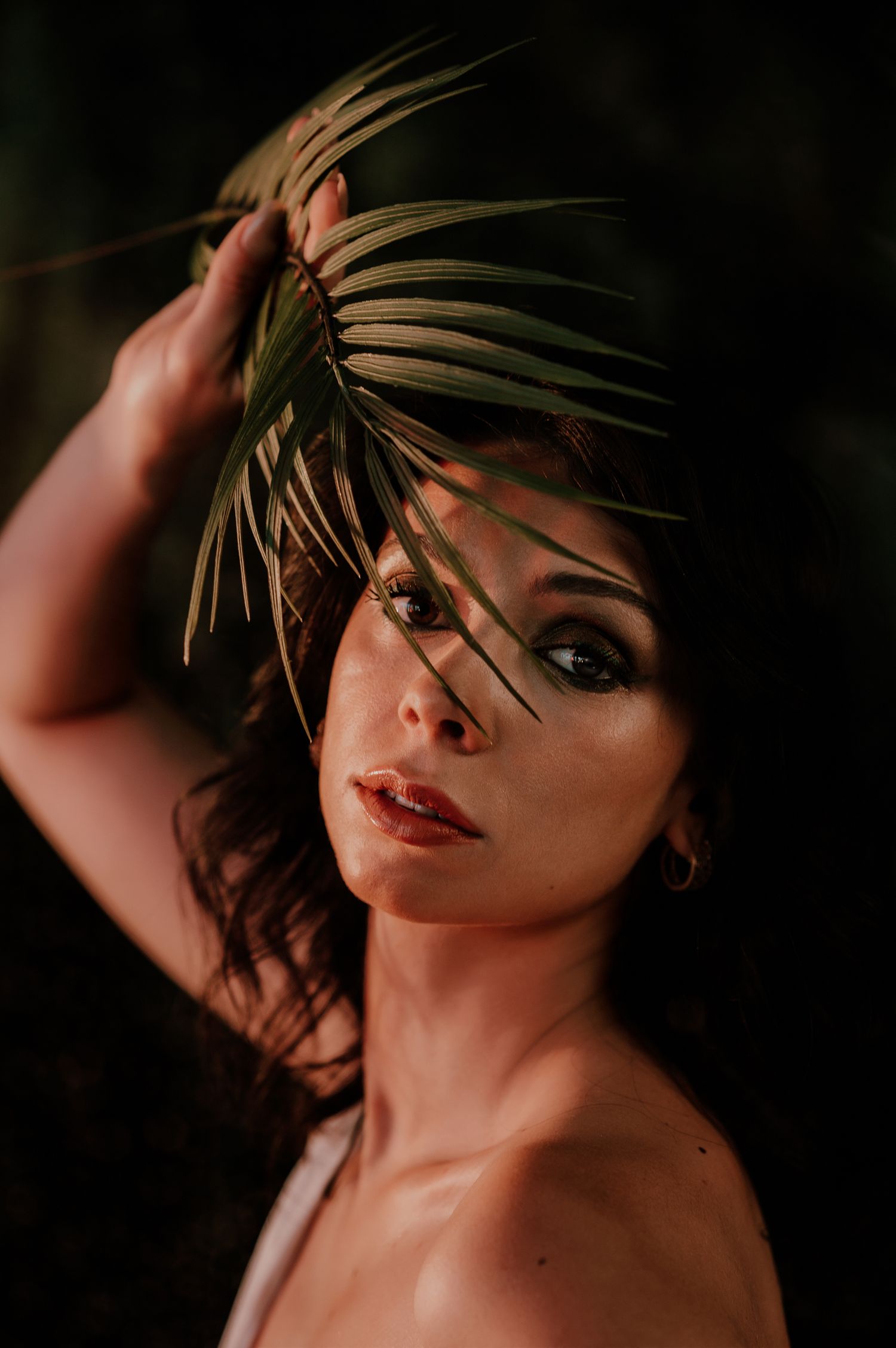 A dramatic portrait series in dark lighting shows a person with red lipstick and feathered accessories posing expressively.