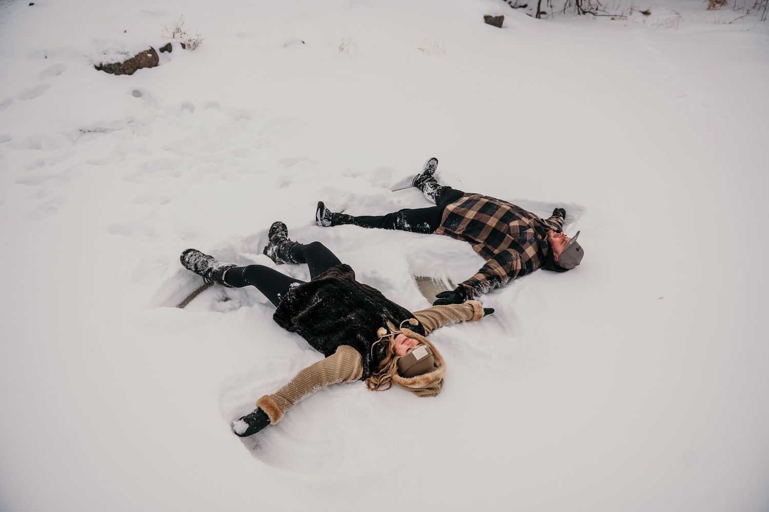 A person lying in fresh snow makes snow angels by moving their arms and legs back and forth to create wing patterns.