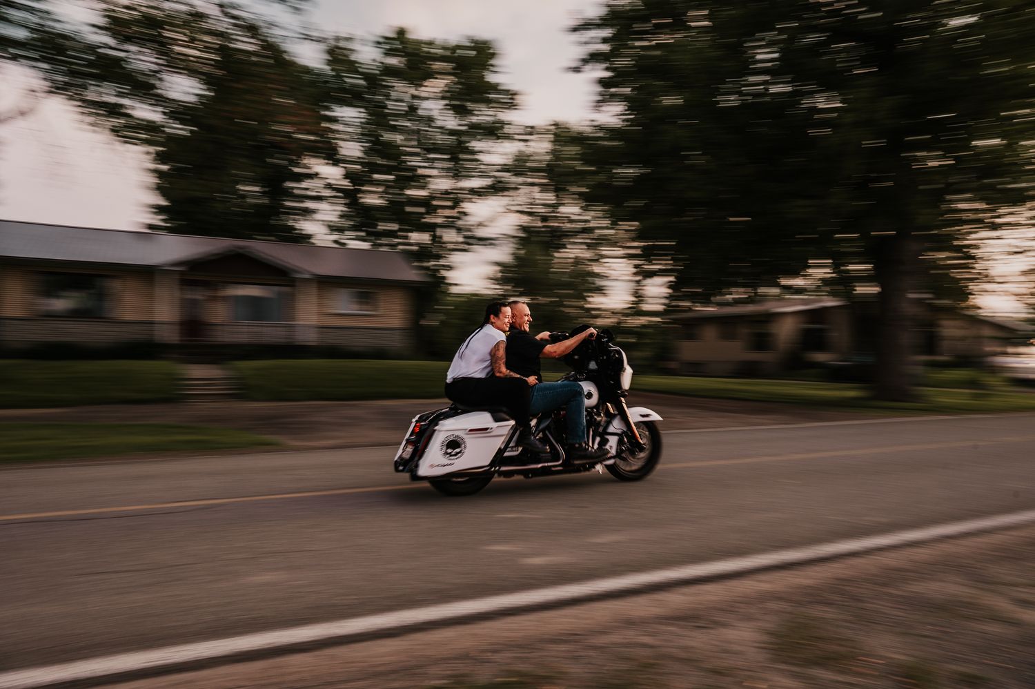Motorcyclist leans into a turn on a winding road during sunset creating a dynamic motion blur effect.