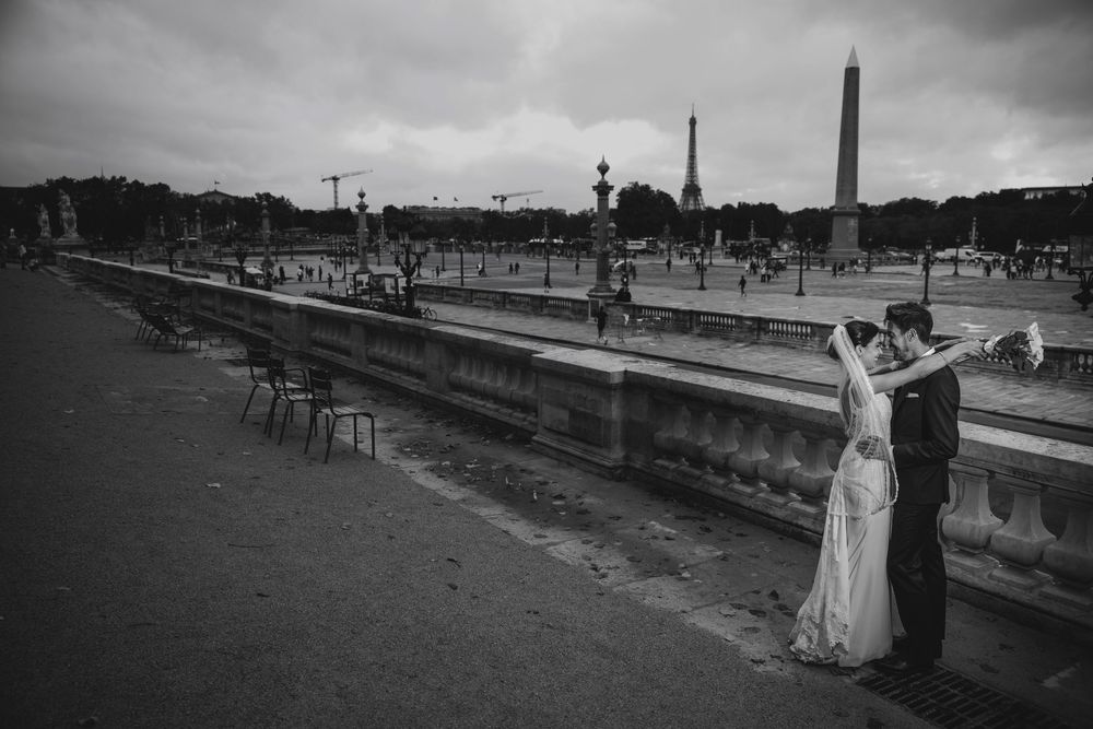 Black and white photo of a bride and groom kissing near the Eiffel Tower at Place de la Concorde in Paris.