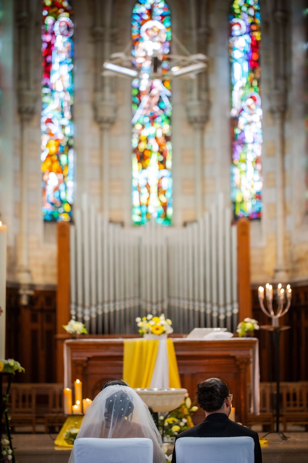 Beautiful stained glass windows and pipe organ in a church sanctuary with wooden pews and soft natural lighting.