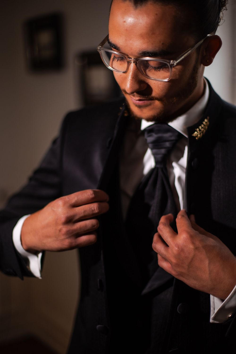 A sequence of photos showing a person in a dark suit adjusting their collar and tie in dramatic lighting.