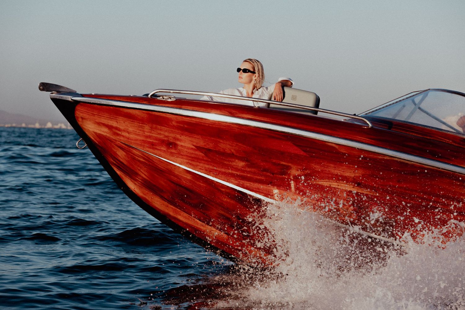 A red wooden speed boat racing across blue waters creating dramatic white wake spray on a cape town photo production.