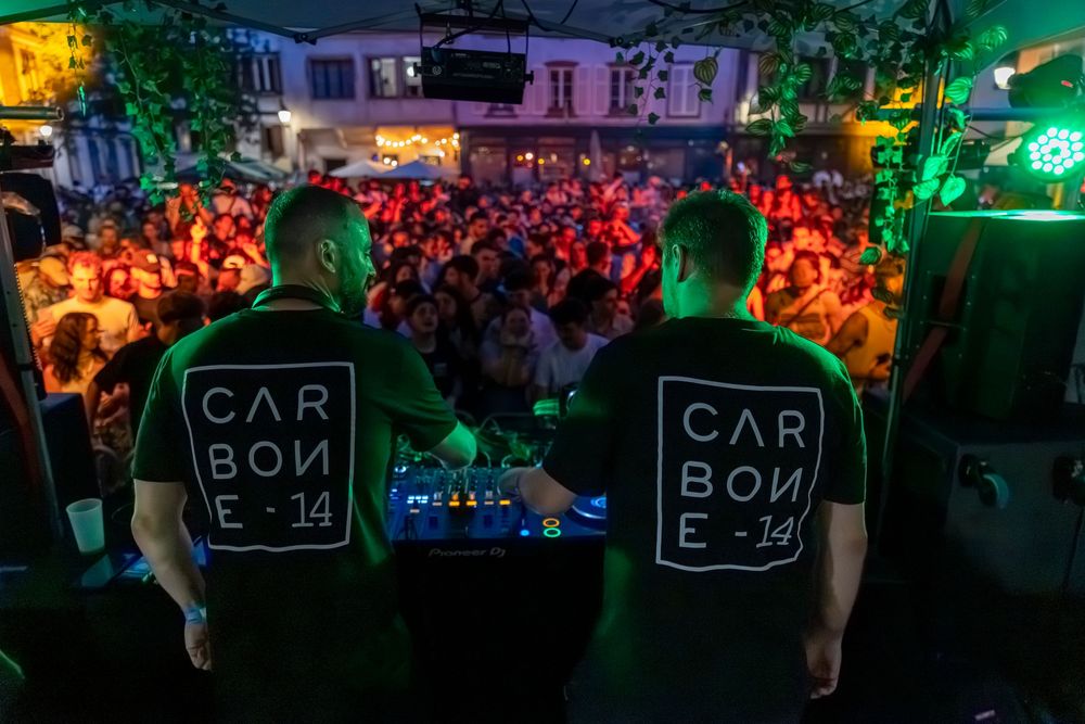 Concert crowd fills nightclub with colorful lights and signs glowing in the dark atmosphere during a live performance.