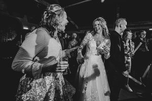 Black and white photo of couples dancing at a wedding reception in a dimly lit venue.