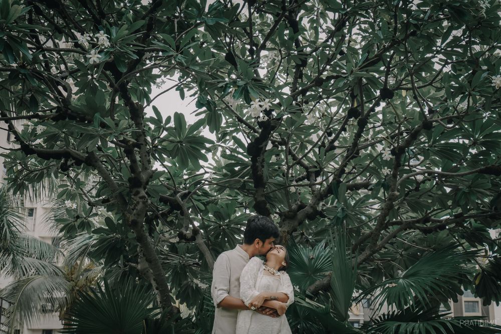 A couple shares romantic moments while walking through lush greenery.