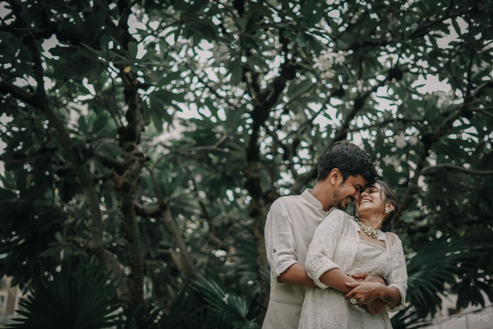 Romantic photoshoot sequence in a tropical garden with white-clad couple.