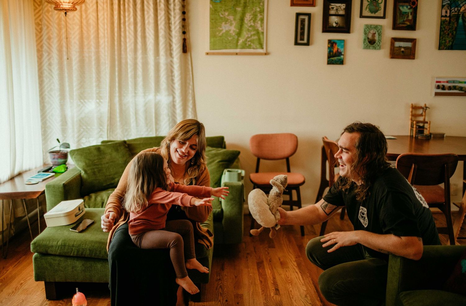 child reaches for toy father has while sitting in mothers lap. portland, oregon family photography rushes & waves