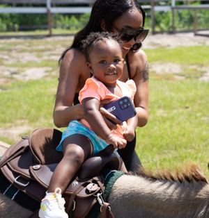 Young child enjoying a horseback riding lesson on a sunny day.