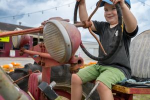 Hands reaching up to interact with farm equipment outdoors.