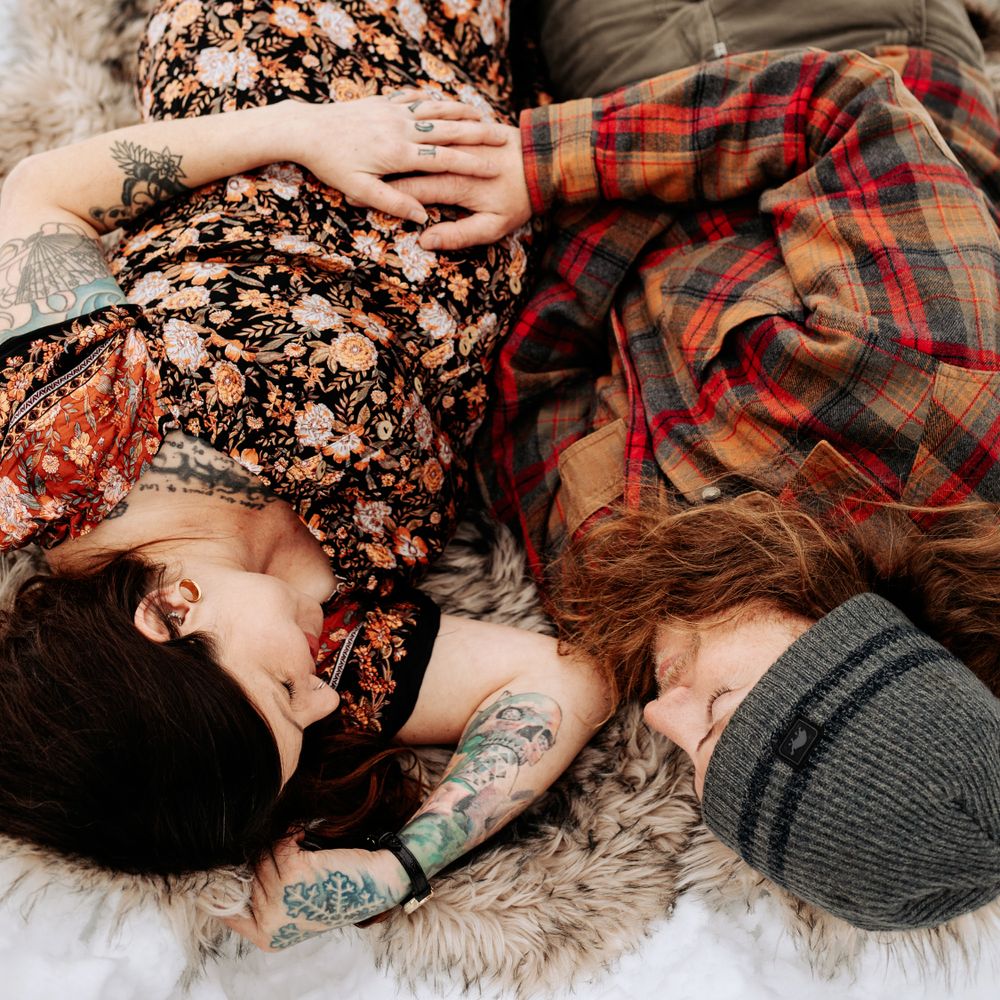 expecting couple laying in a snow covered meadow during a wintery mountain maternity shoot in Lake Tahoe