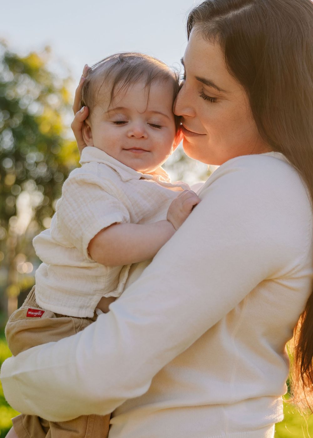 Intimate family portraits showing parent and baby sharing affectionate moments in soft lighting.
