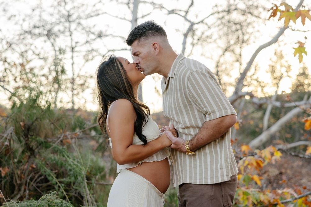 A couple shares romantic moments in a desert landscape during a golden sunset photoshoot.