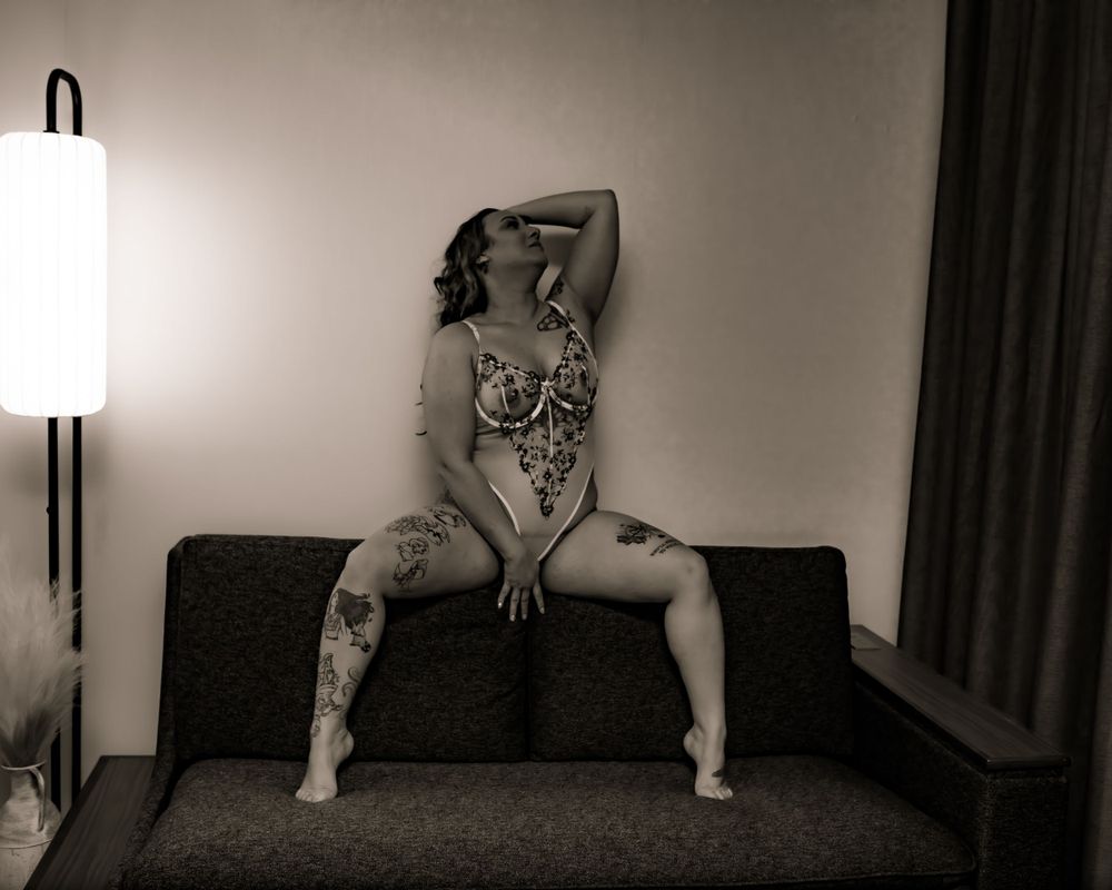 Artistic black and white portrait on dark sofa with moody lighting.