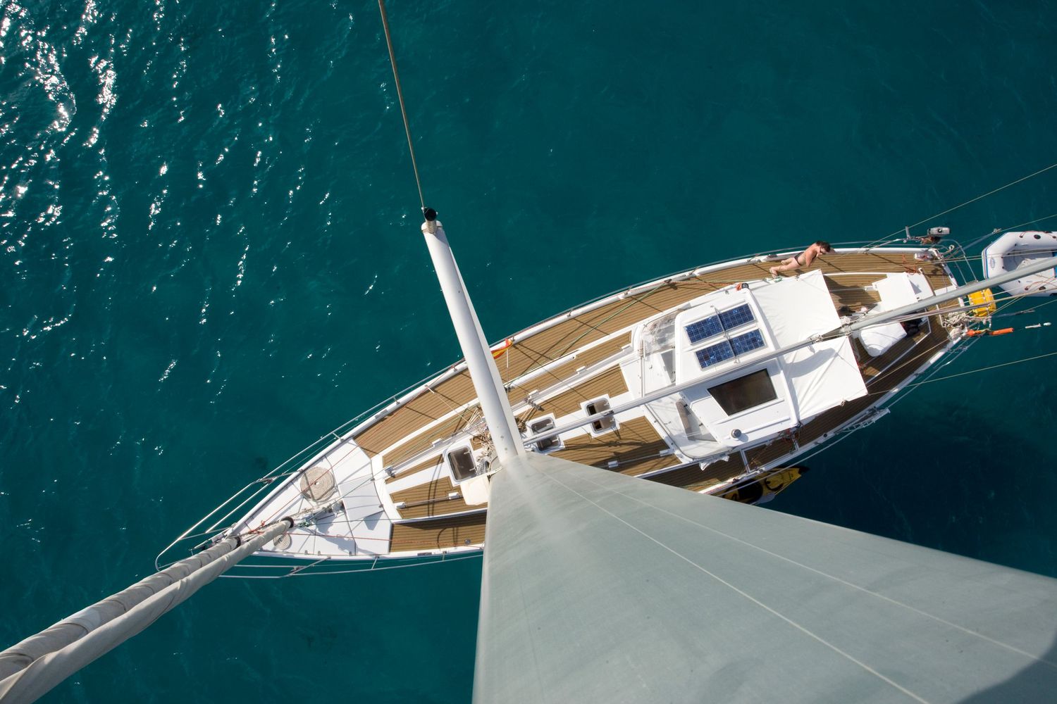 Aerial view of a luxury sailing yacht on turquoise ocean waters from the mast perspective.