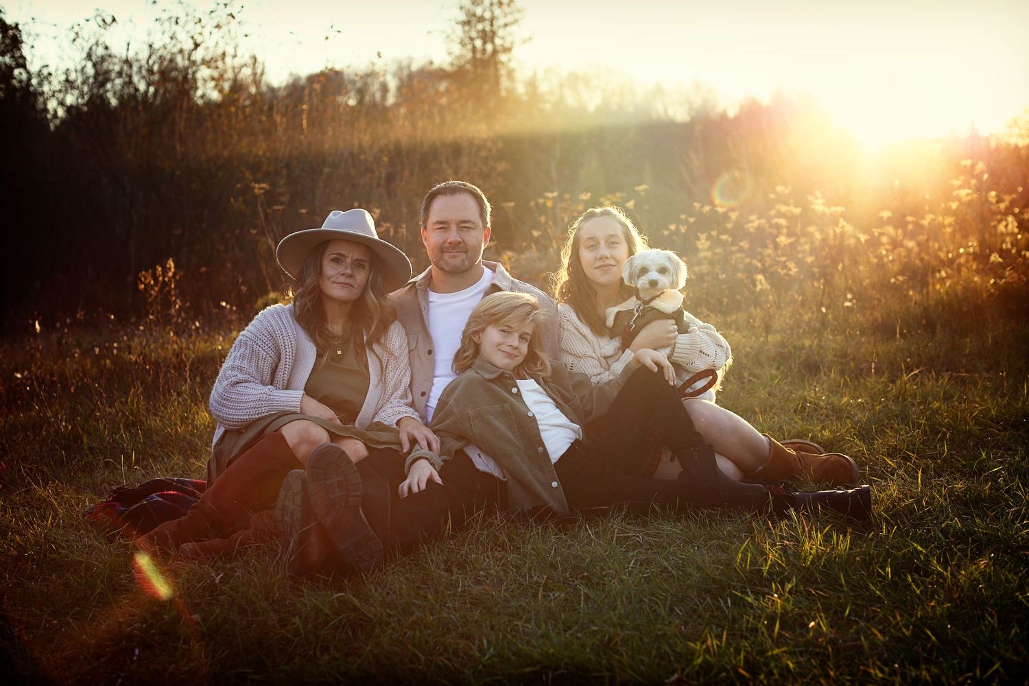 Family gathered on grassy hillside during golden sunset hour.