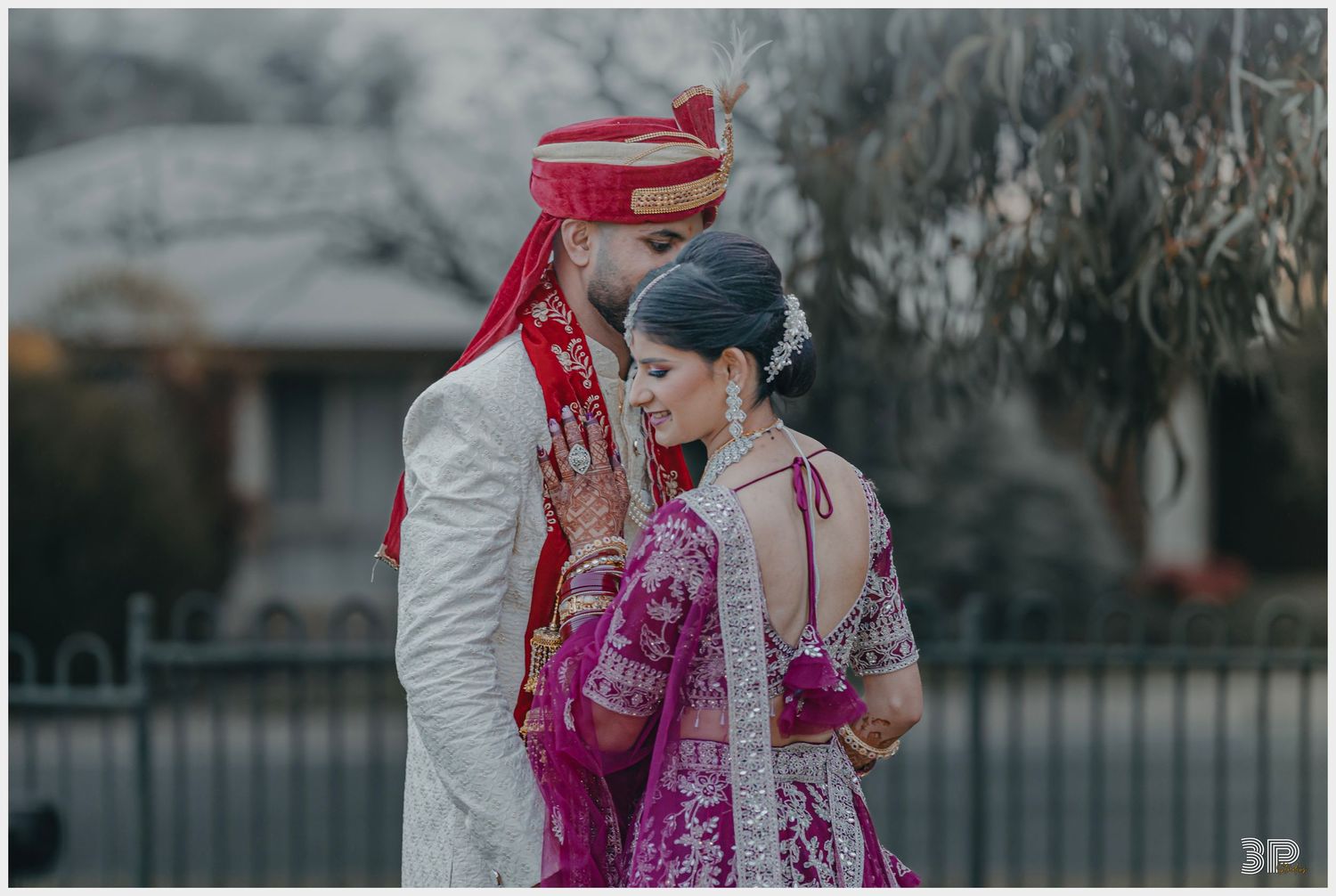 Bride and groom in traditional attire share an intimate moment during an outdoor photoshoot.