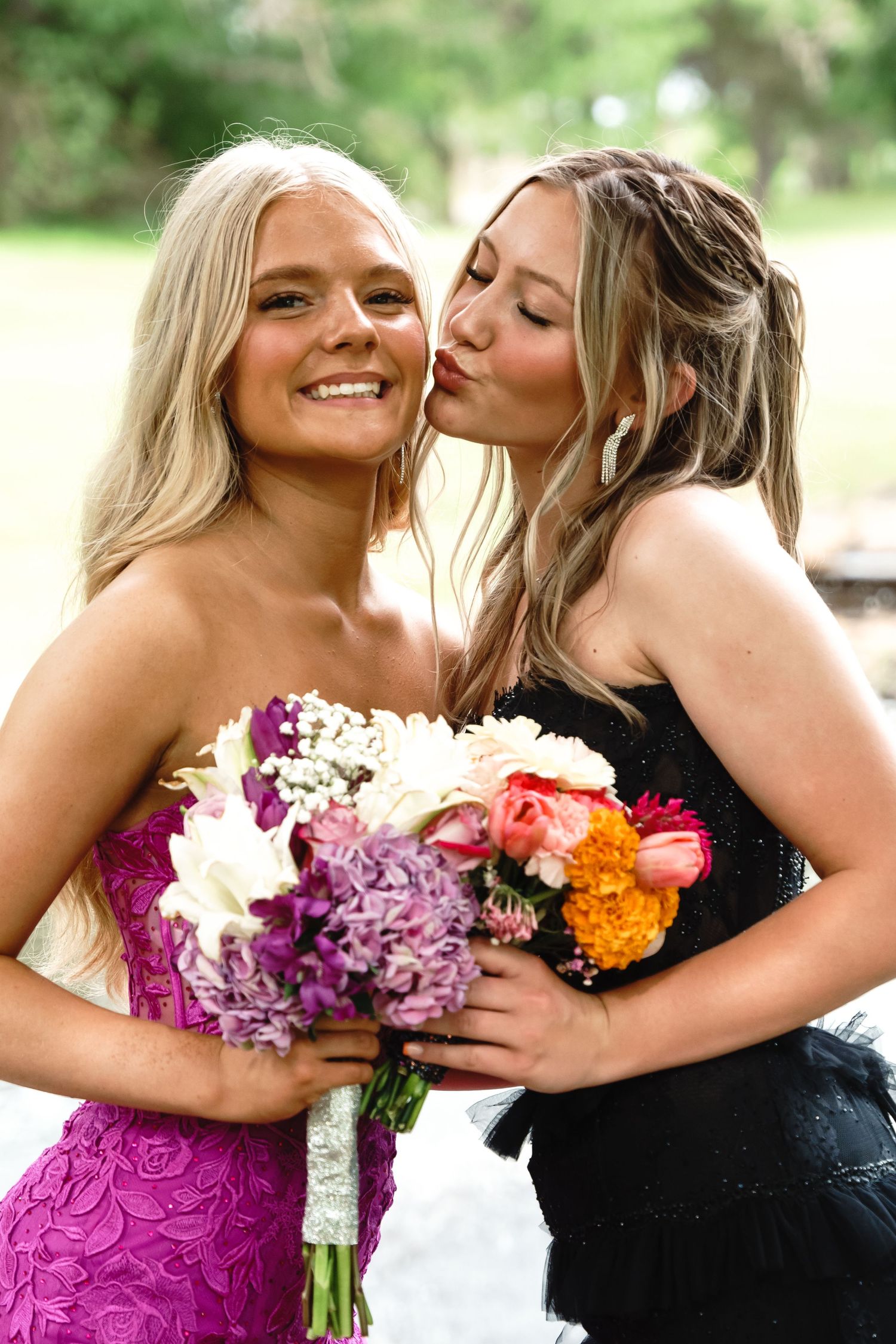 Two friends share a joyful moment with a vibrant bouquet featuring purple, pink and orange flowers.