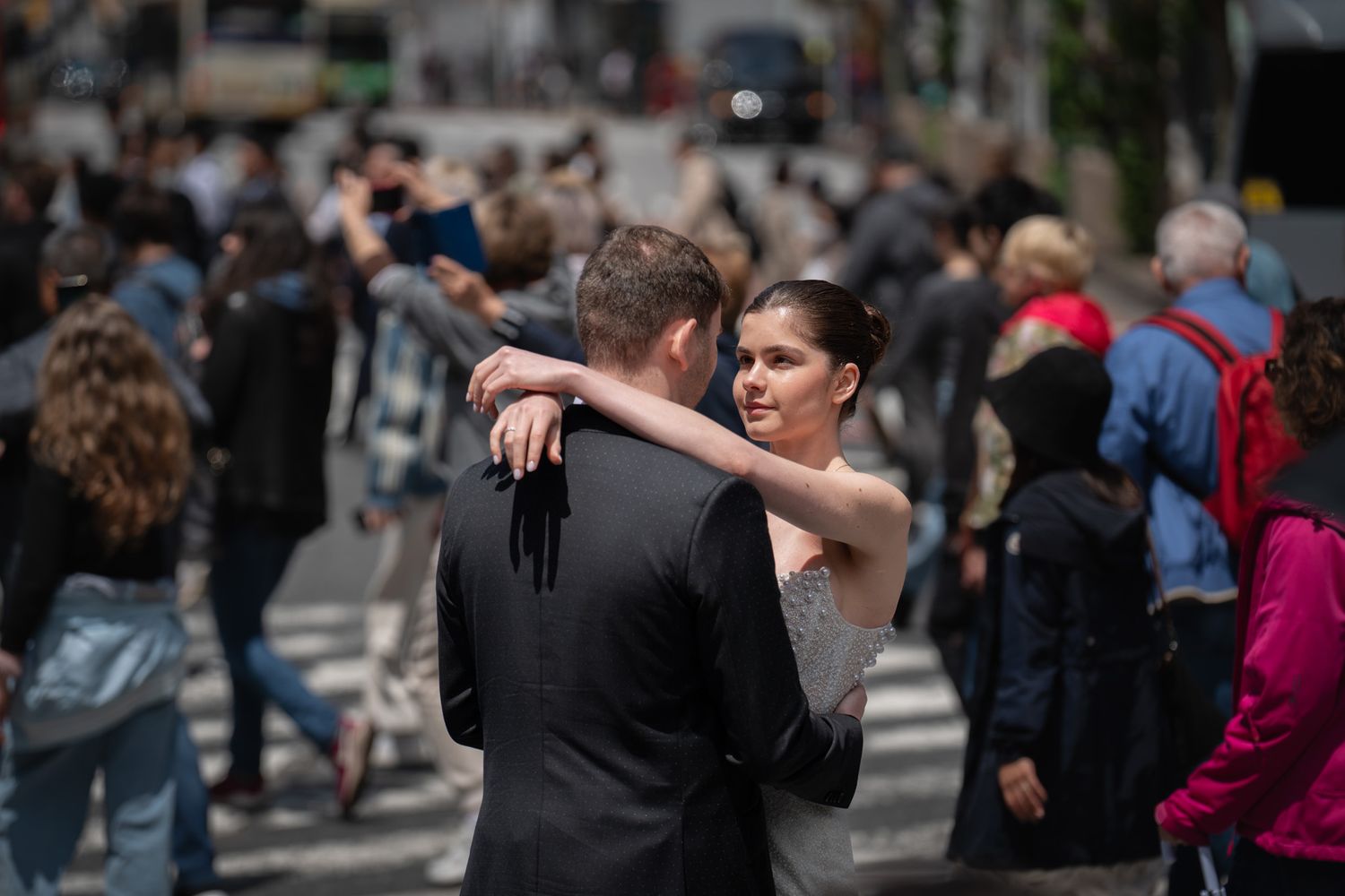 A couple dances together on a crowded street surrounded by passersby.