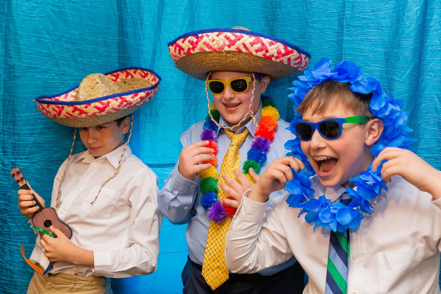 Three people in Mexican sombreros and festive attire posing with sunglasses against a blue backdrop.