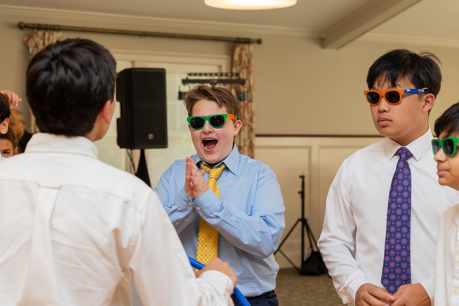 A festive celebration with people wearing sunglasses and ties in an indoor venue.