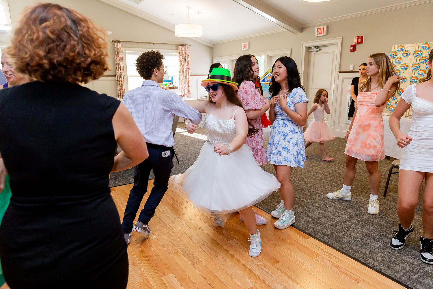 People dancing and celebrating at a party with festive attire and decorative hats.