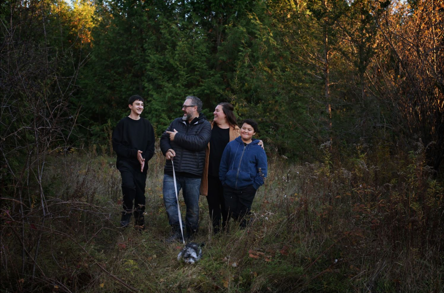 Group sharing laughter together on a wooded trail at dusk.