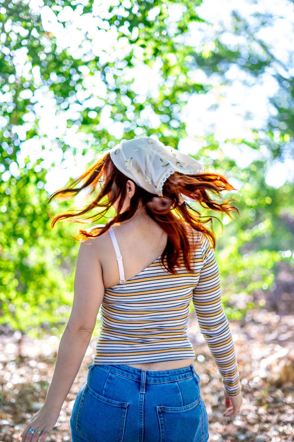Dynamic shot of hair movement under white cap with striped shirt against green foliage.