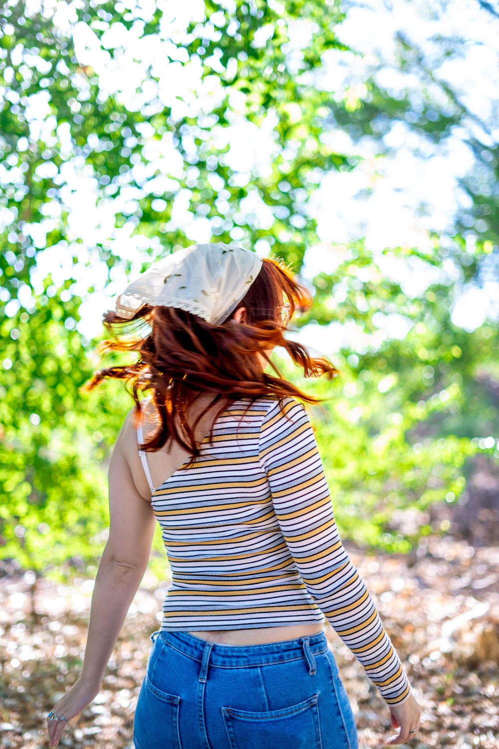 Dynamic shot of someone with flowing hair spinning in a sunlit forest setting.