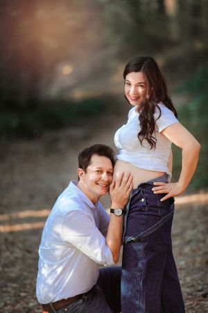 A tender maternity photo moment captured in a natural outdoor setting.