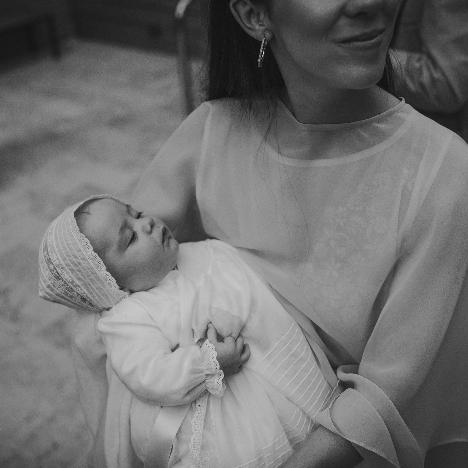 fotografía elegante de bautizo. bebe con faldón y capota en los brazos de su mama en la iglesia. Chamartin.