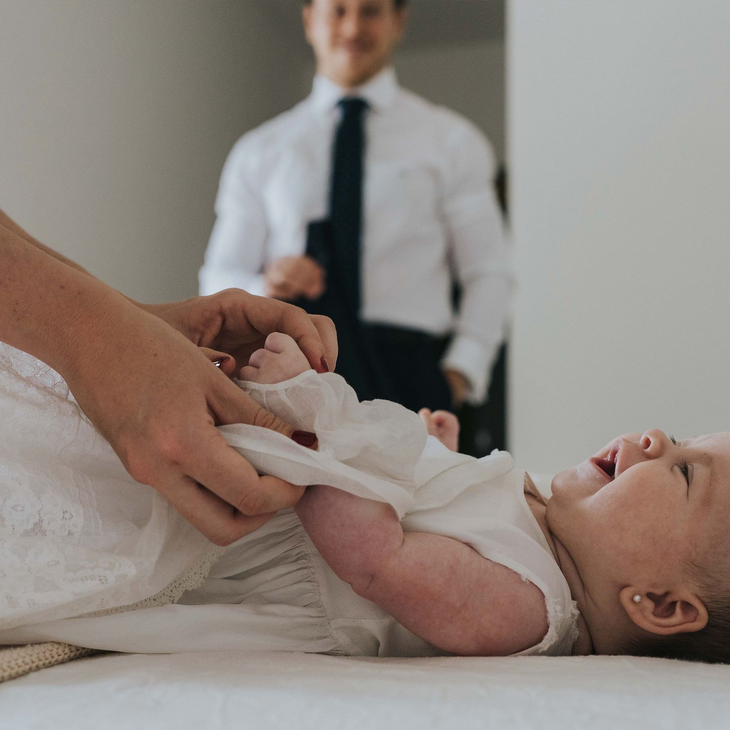 escena cotidiana de mamá preparando la niña y papá las mira con ternura. cada foto cuenta una historia única