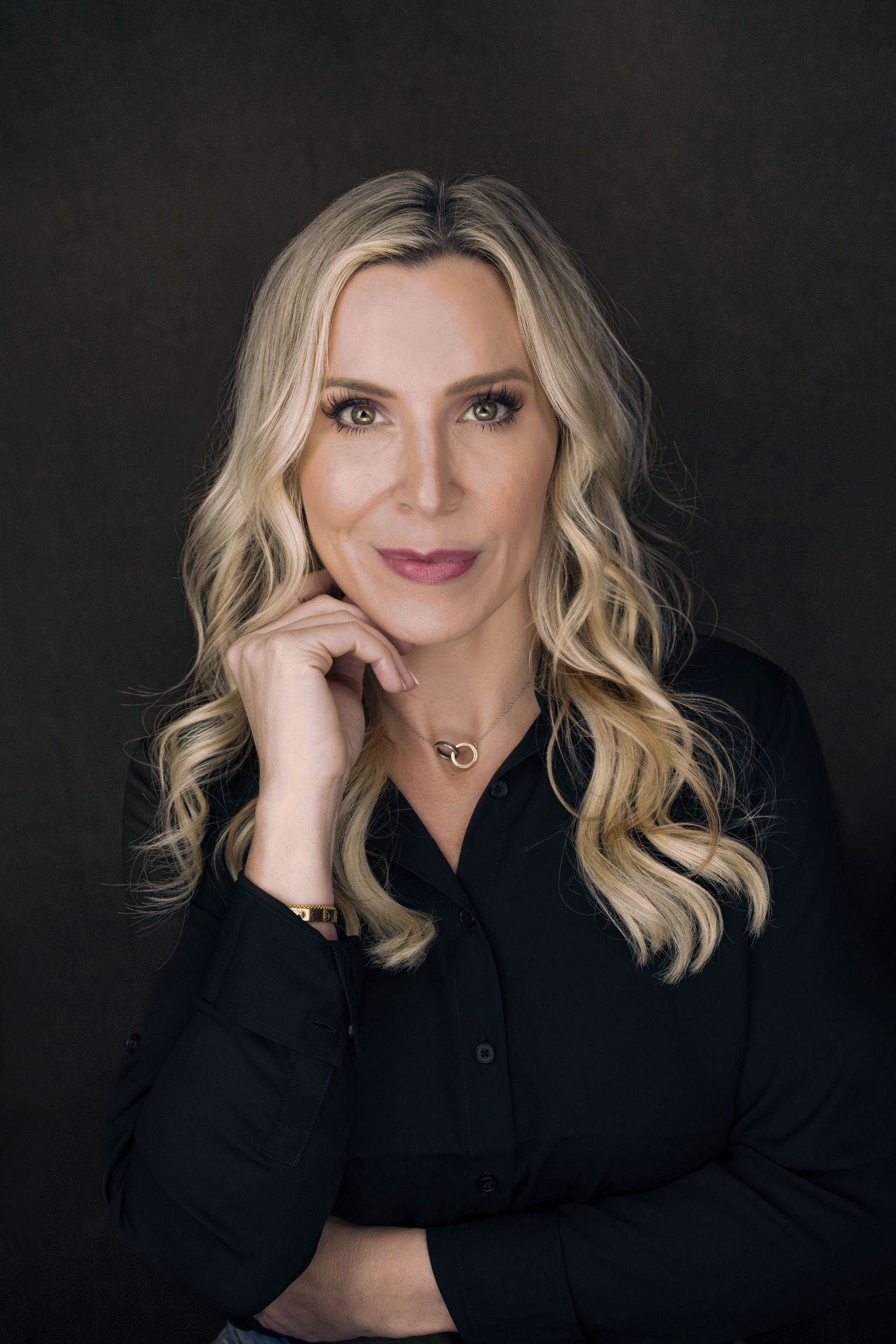 Studio portrait with dramatic lighting featuring subject in black button-down shirt.