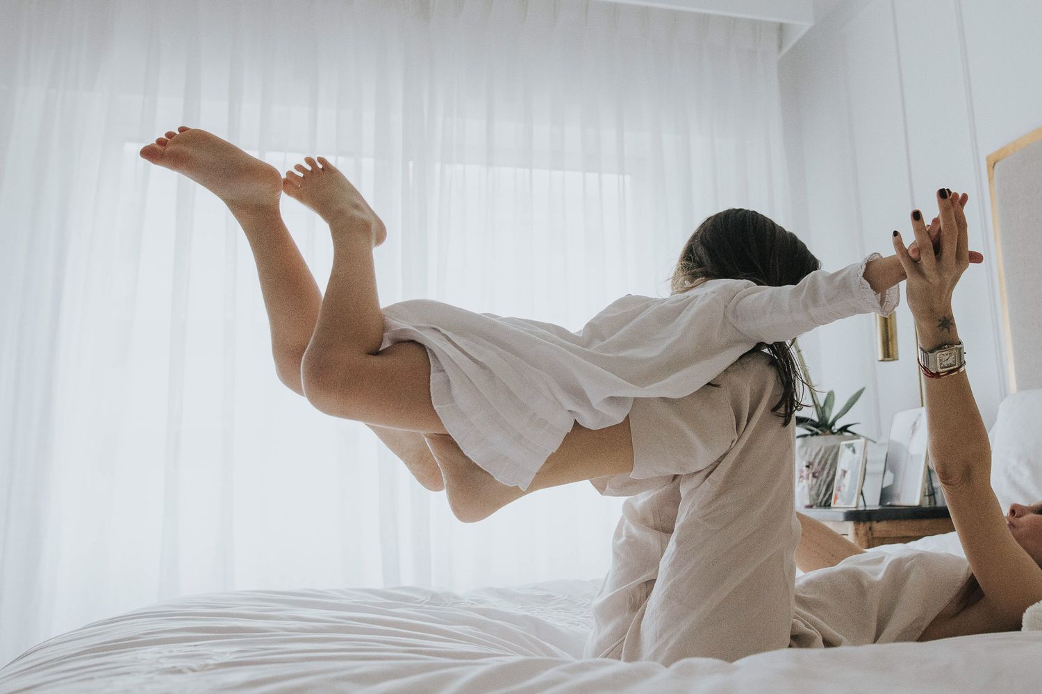 cuando volar en las piernas de mamá era volar de verdad. madre y hija jugando en la cama. momentos sencillos de la vida