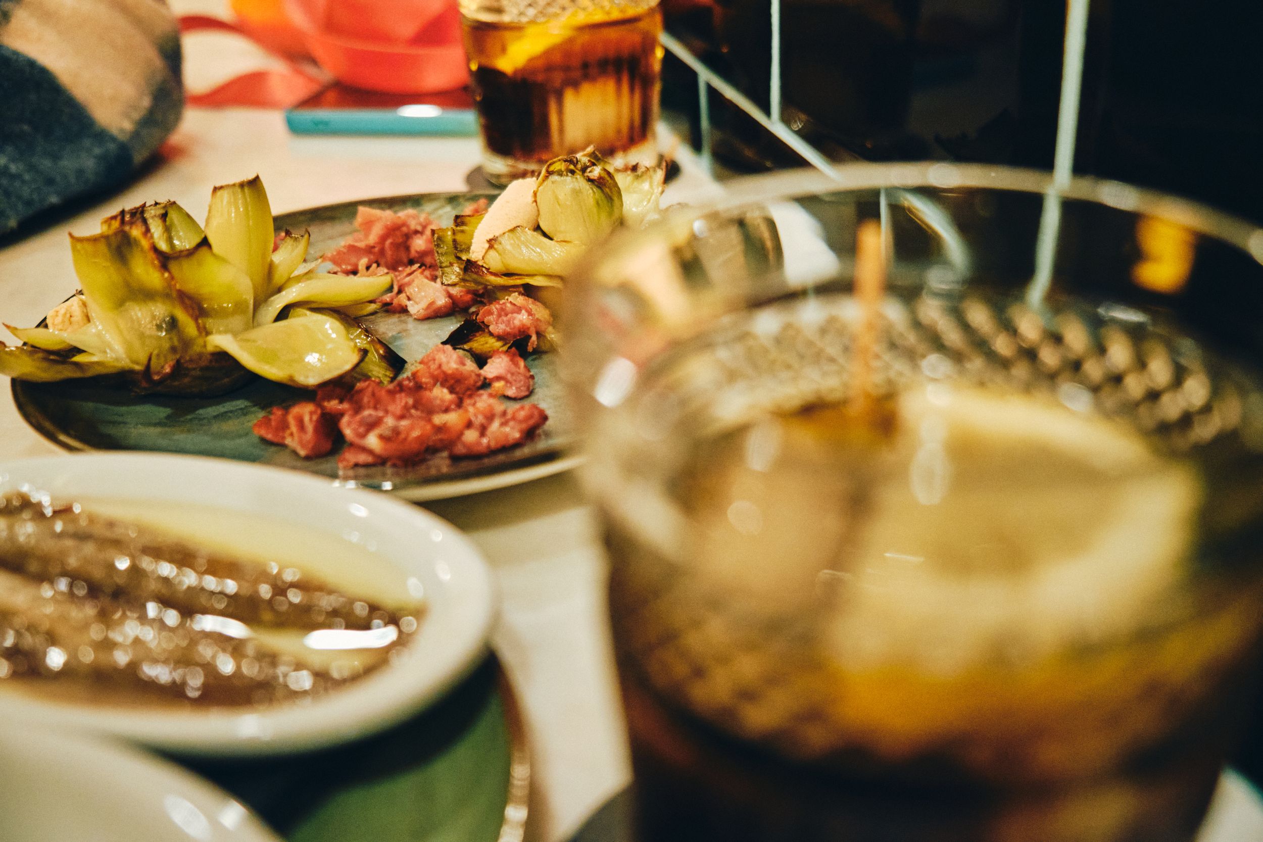 Various tapas and drinks served on a restaurant table with atmospheric lighting.