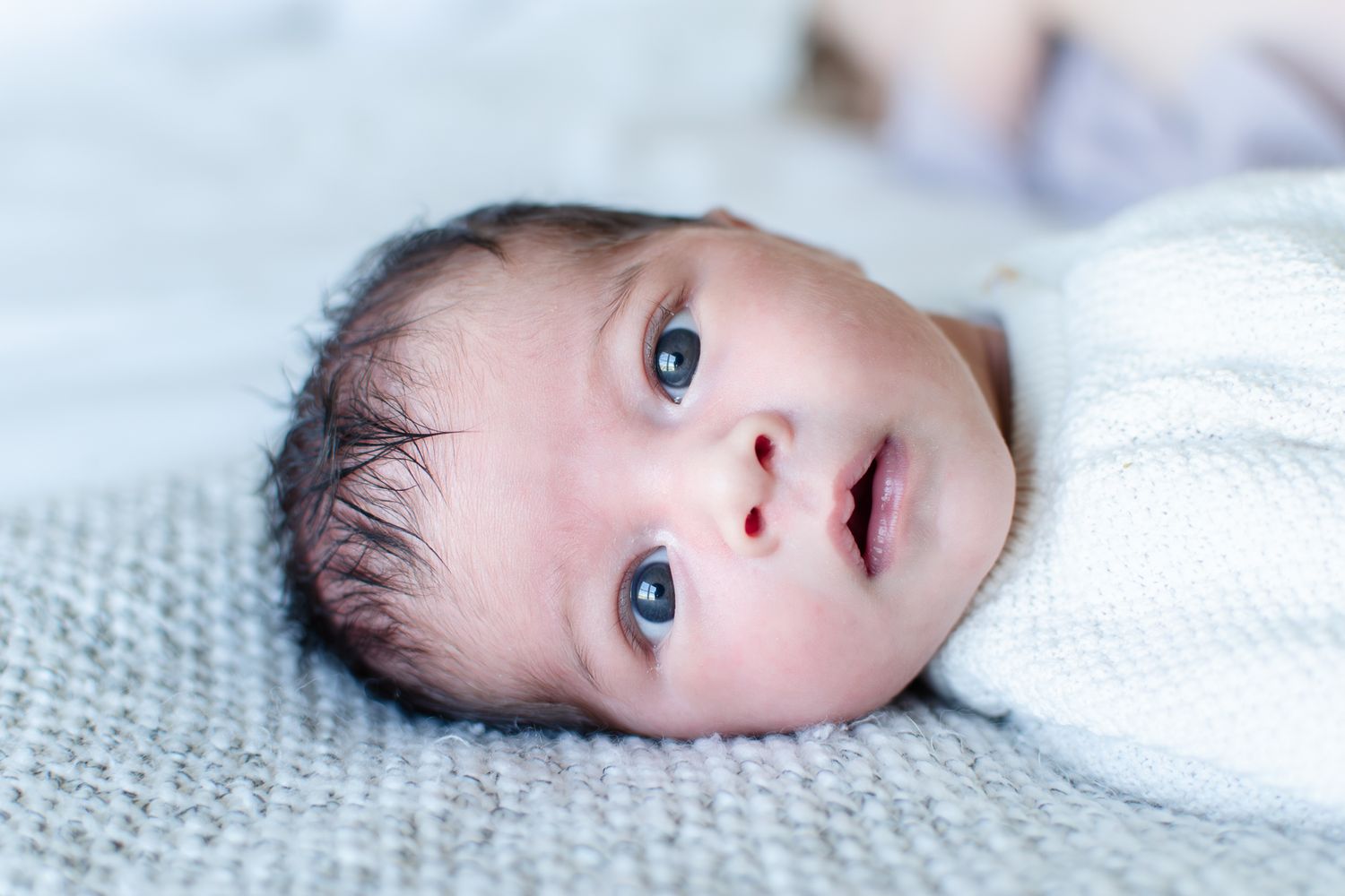 Baby girl laying on family bed at her newborn session at home.