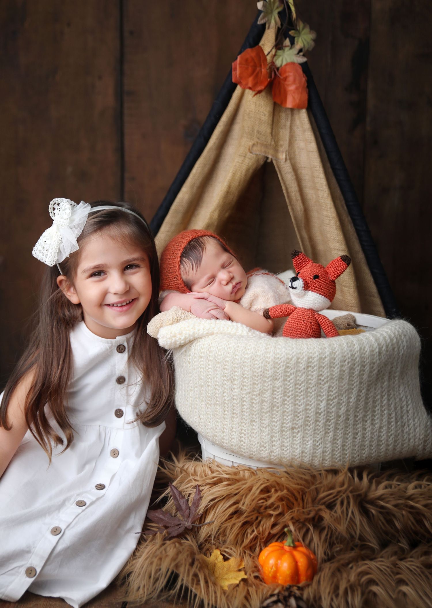 Newborn photo setup with teepee, stuffed fox, and autumn decor.