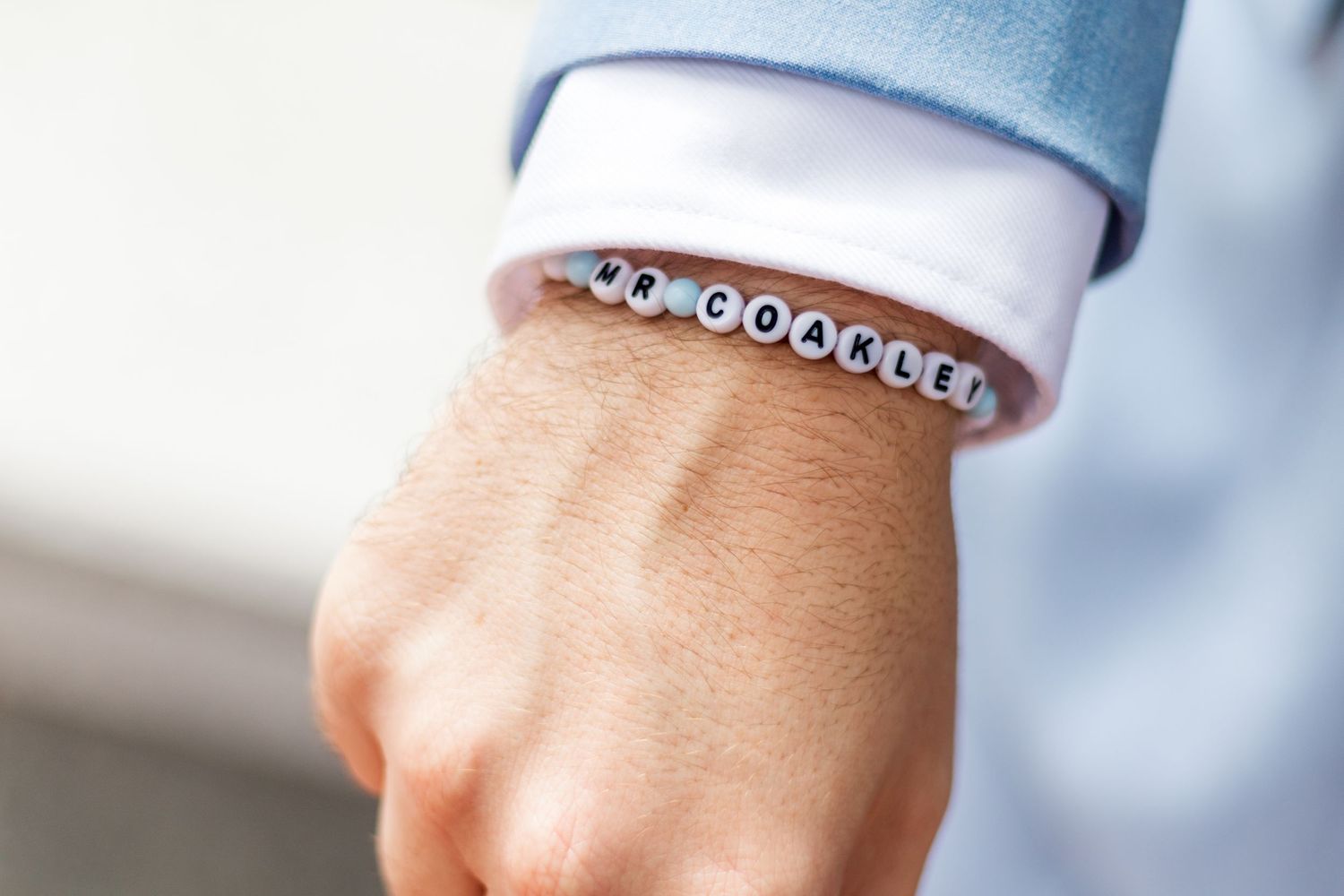 Silver beaded bracelet worn with light blue shirt sleeve.