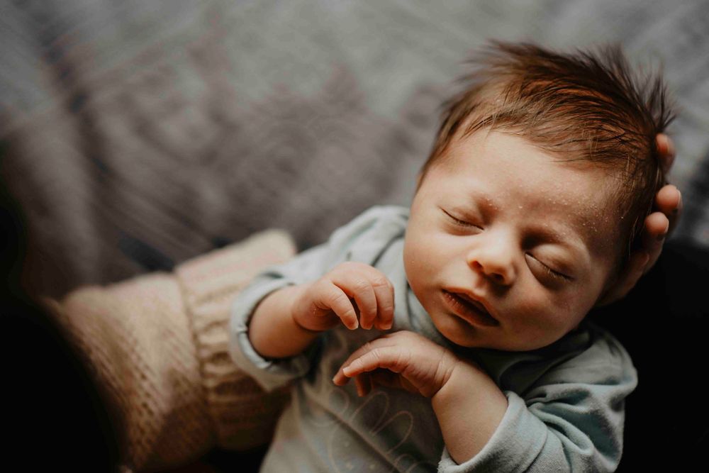 Recém-nascido dormindo serenamente, envolvido em luz suave e calor humano – um retrato íntimo e terno da nova vida.
