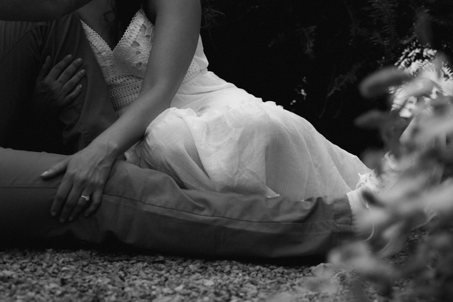 Black and white photo showing details of a white wedding dress against casual attire.