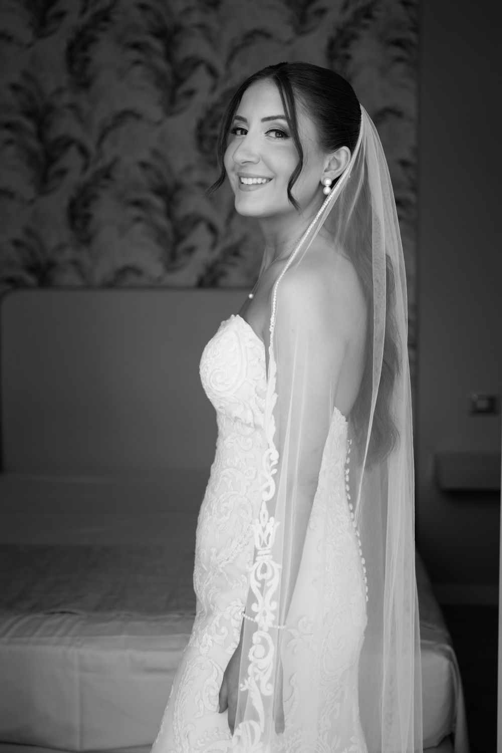 Black and white portraits of a bride wearing an elegant lace wedding gown and veil.