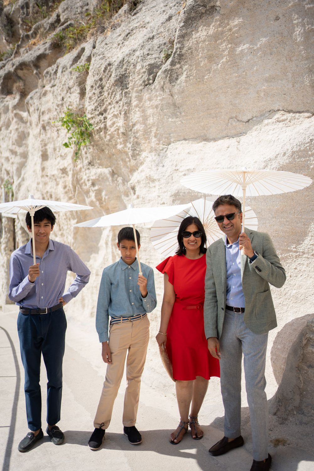 Group photo sequence showing people posing with parasols against limestone wall.