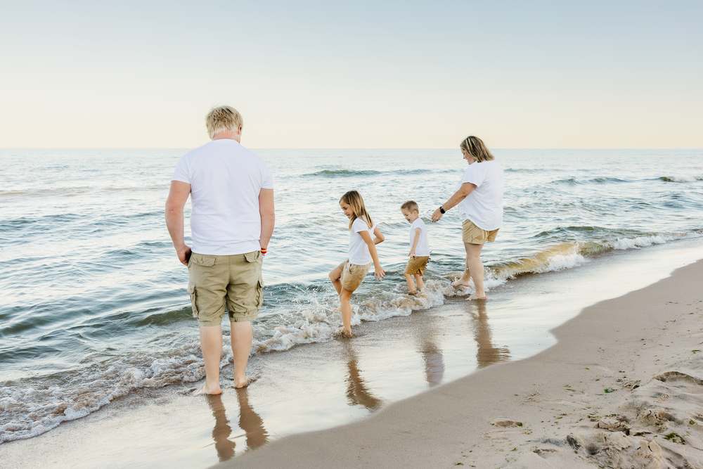 Group enjoying a relaxing stroll on the sandy beach with ocean waves and golden sunlight.