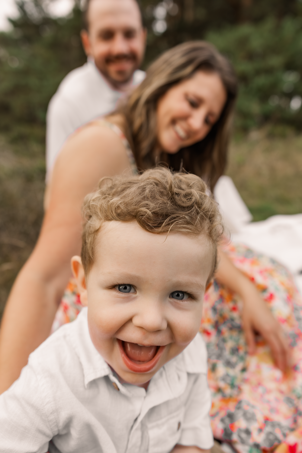 A series of close-up portraits showing a young child in a white shirt smiling and laughing against a blurred background.