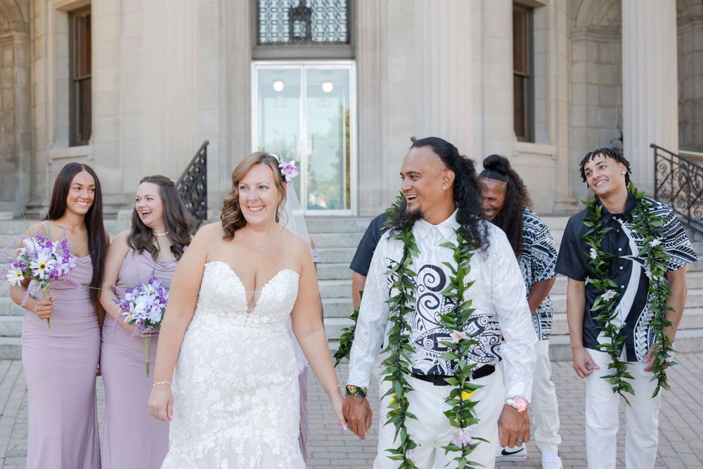 Bride and groom walking with bridal party laughing and enjoying a candid moment together.