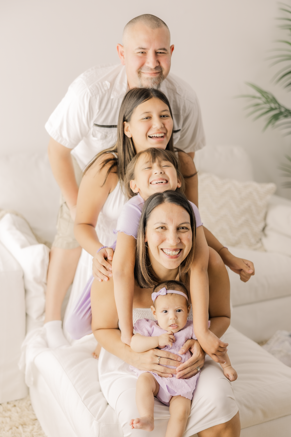 A happy family shares joyful moments together while relaxing on a white bed in casual attire.