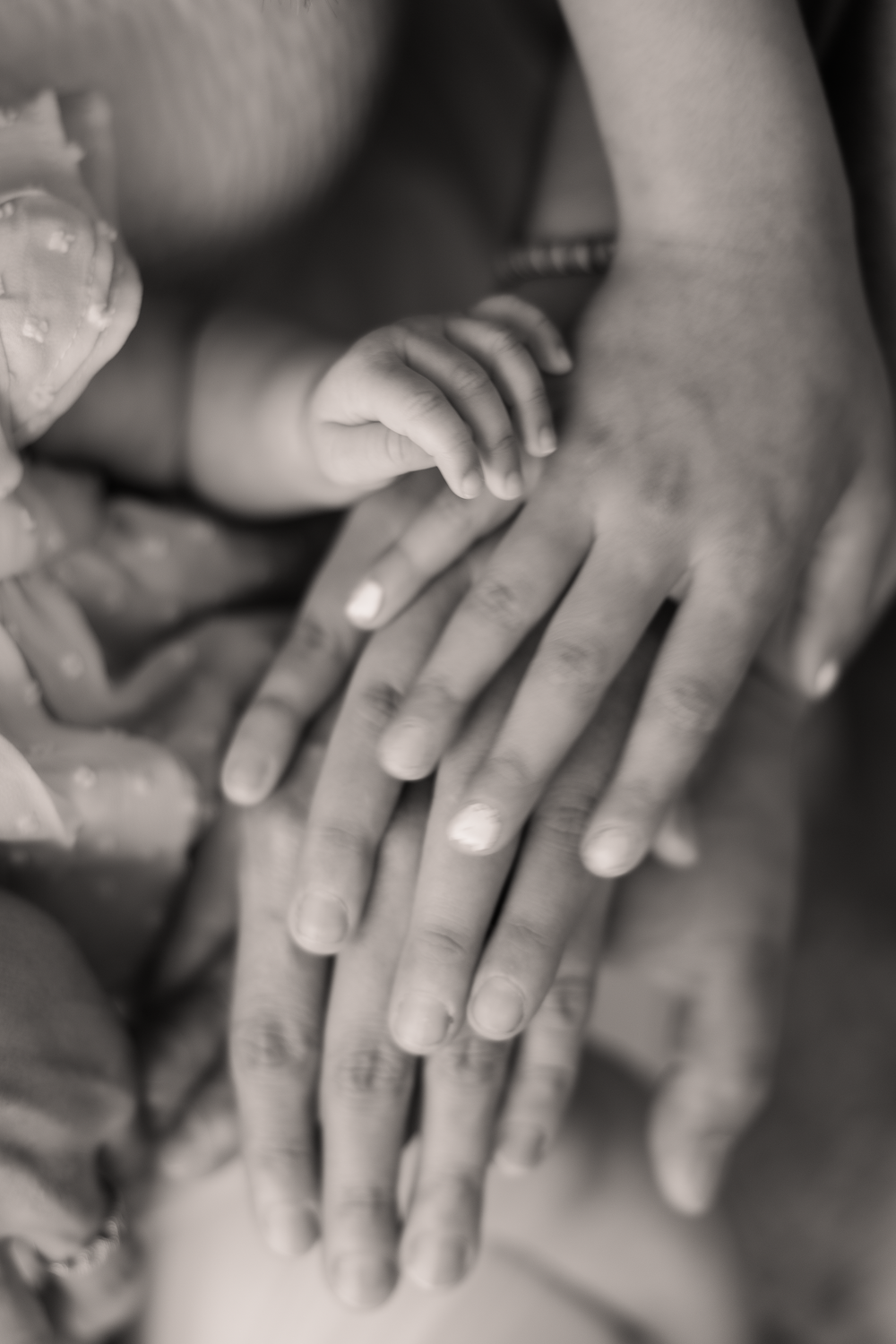 Black and white close-up photo of hands touching in a gentle, intimate gesture.