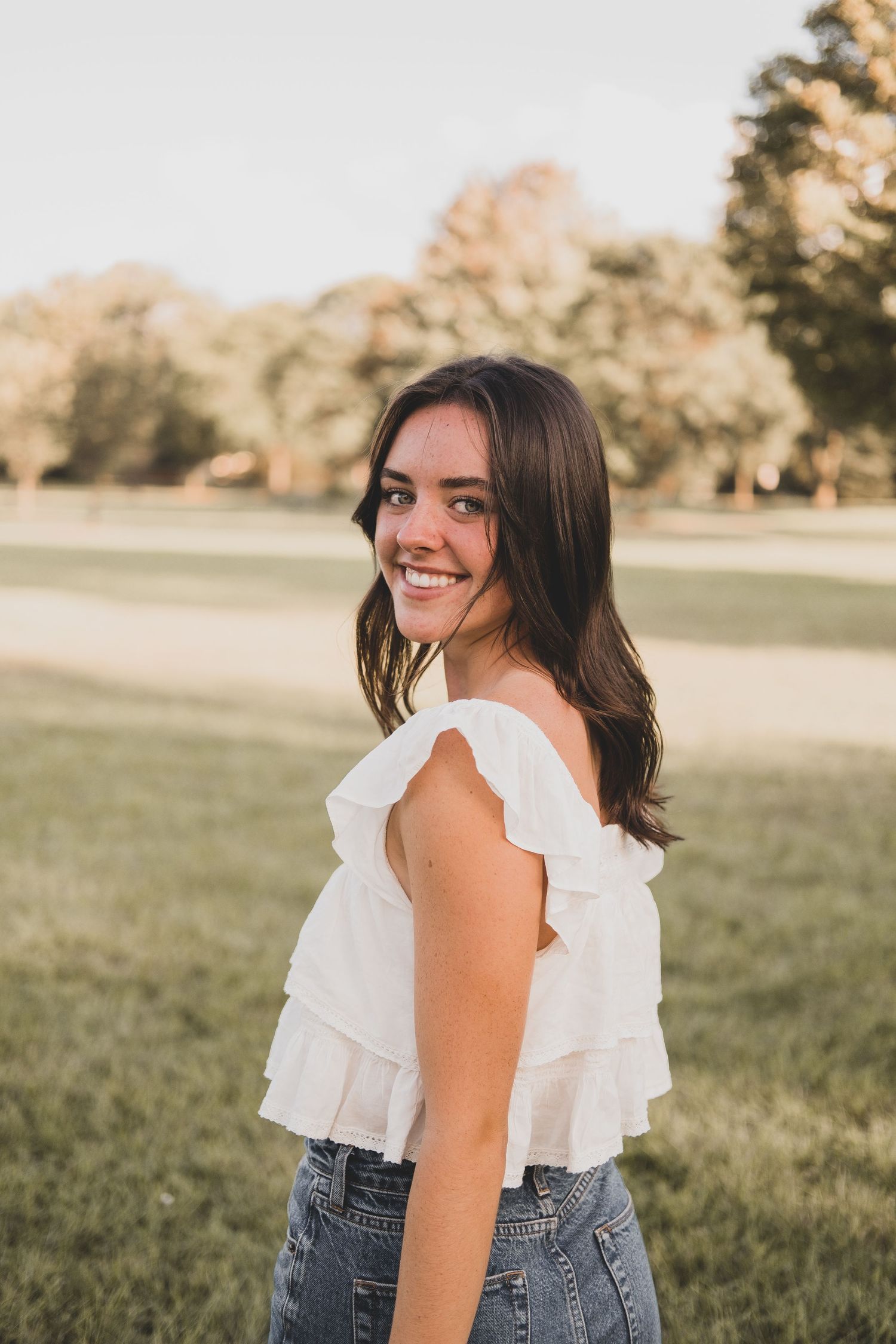 White ruffled top and denim captured in golden hour lighting.