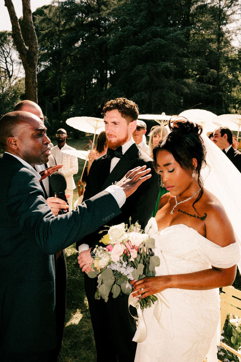 Wedding ceremony moment captured outdoors with bouquet and guests.