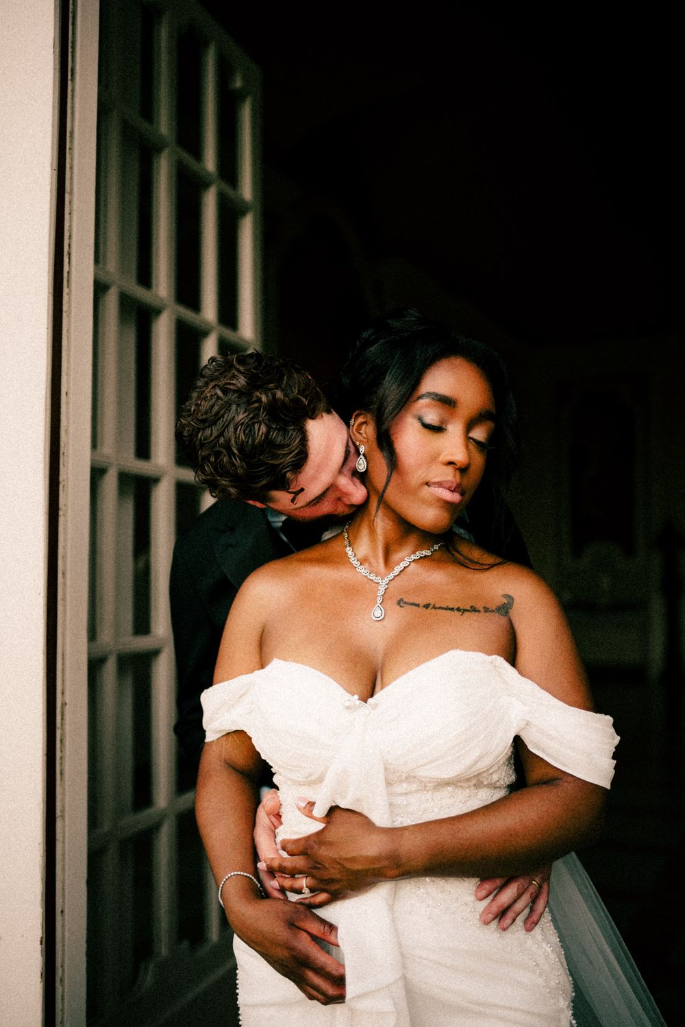 Intimate wedding portrait capturing a tender moment between newlyweds against a dark background.